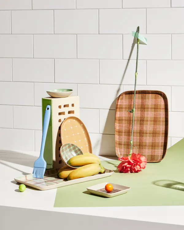 Various ceramic objects by Simone Fennel in front of a wall with tiles and a green paper
