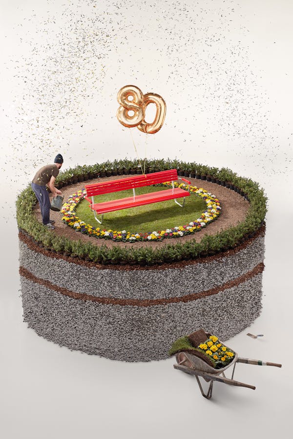 Studio shot of a red garden bench on a trompe-l'oeil cake made of gravel and flowers