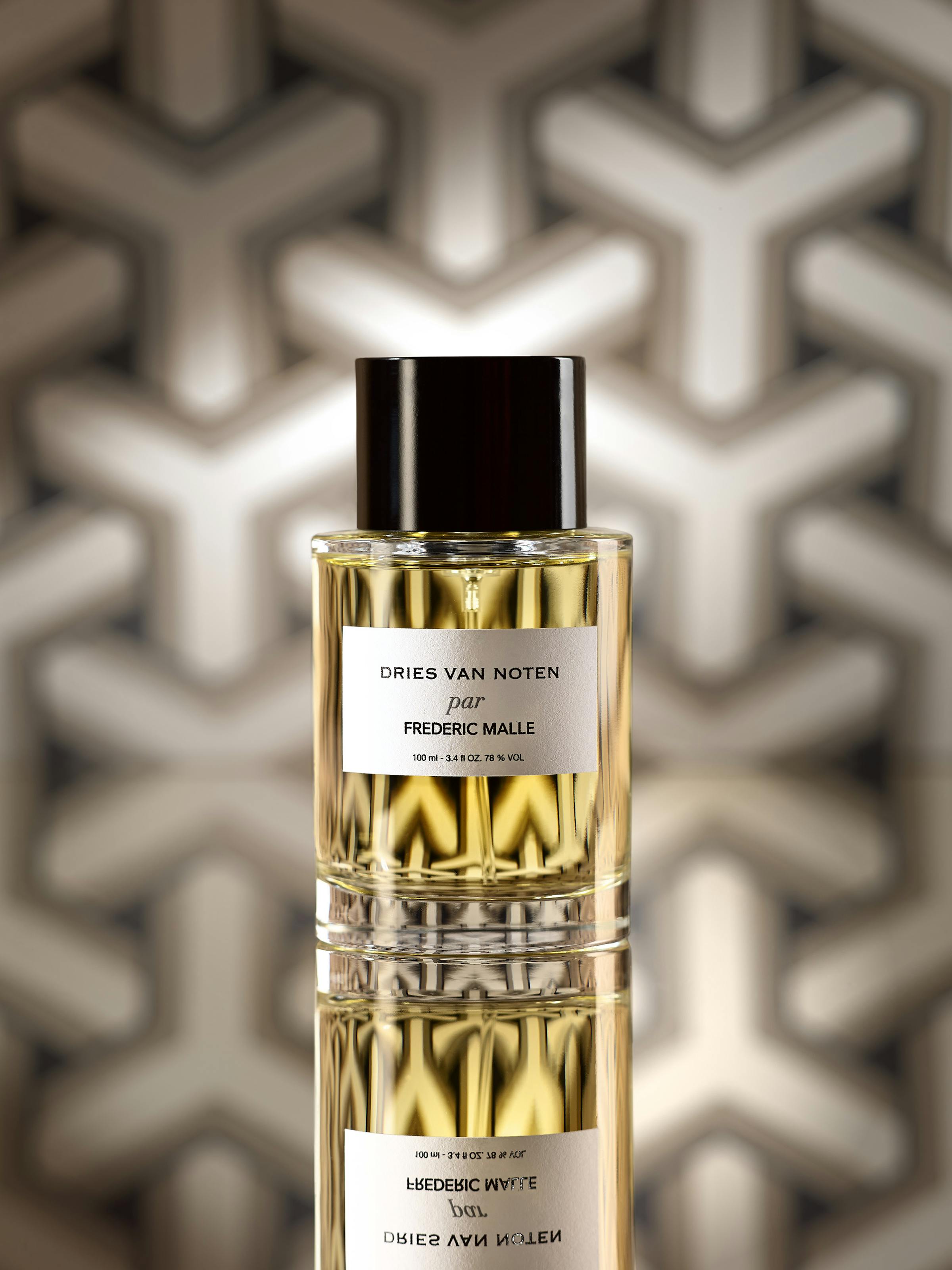 A standing perfume bottle in front of graphic wallpaper