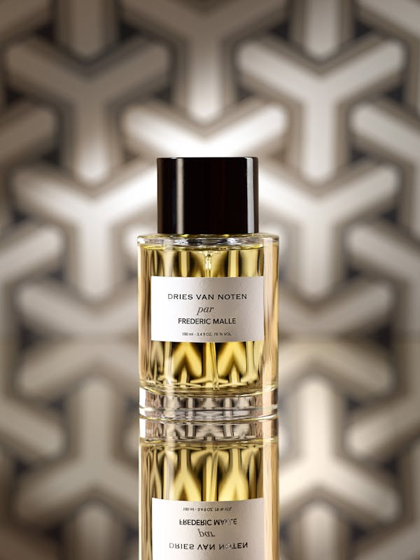 A standing perfume bottle in front of graphic wallpaper