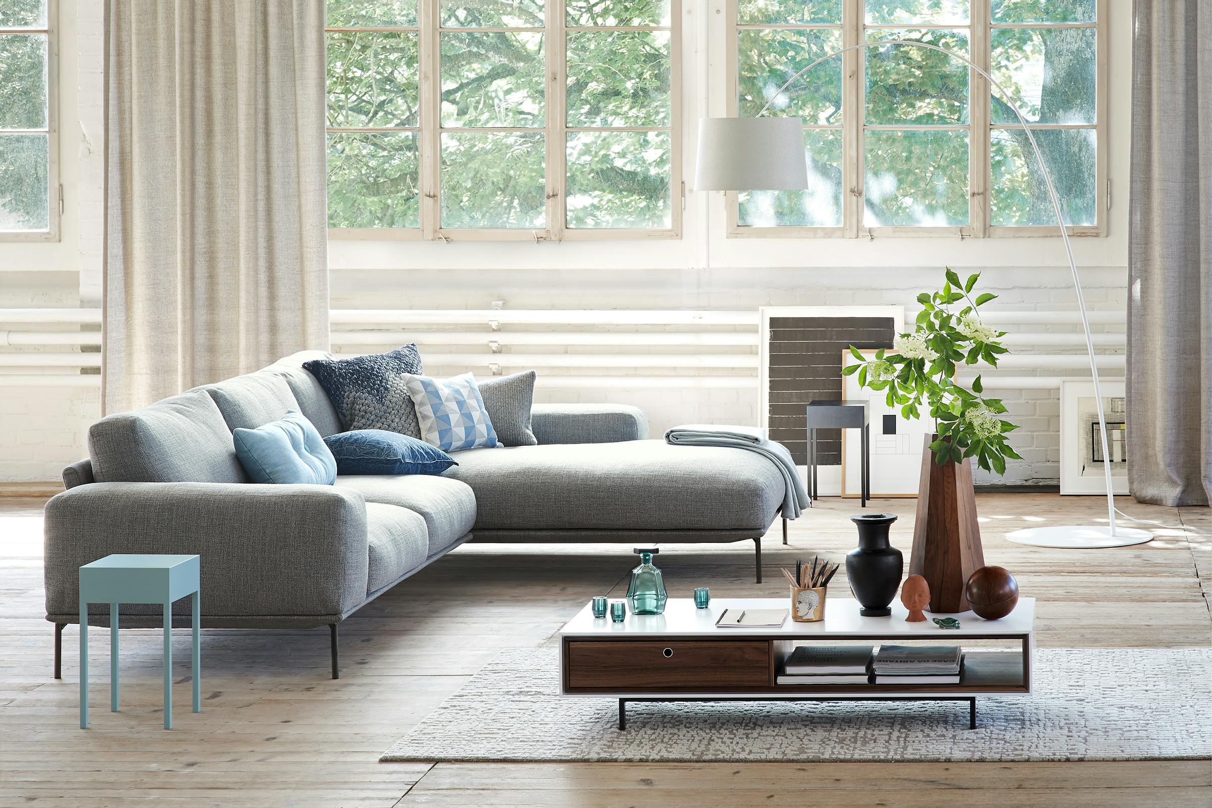 Sofa with recamier in front of a window front in a factory loft on a wooden plank floor