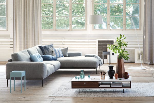 Sofa with recamier in front of a window front in a factory loft on a wooden plank floor