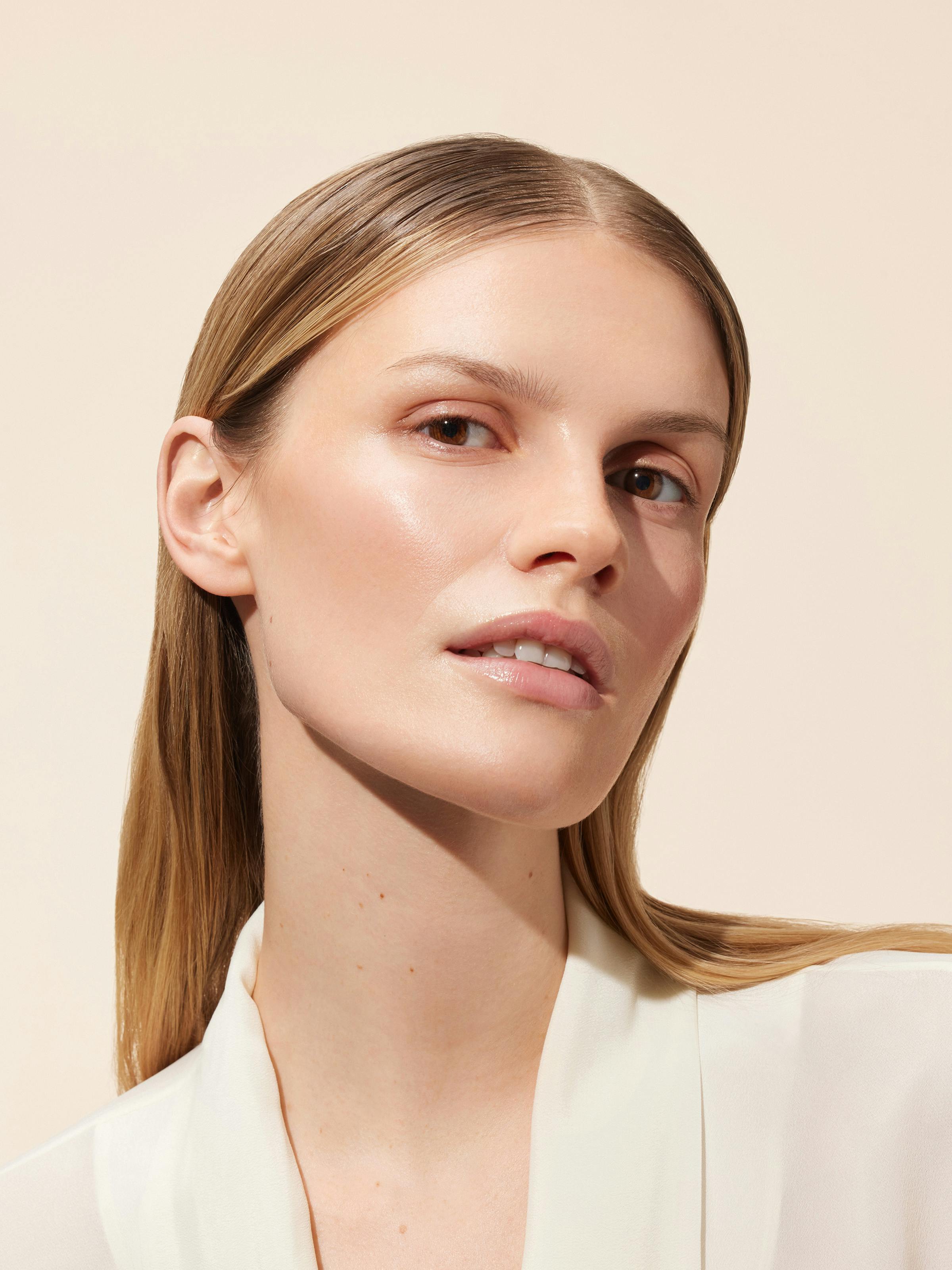 Beauty shot of a blonde woman in front of a light beige background