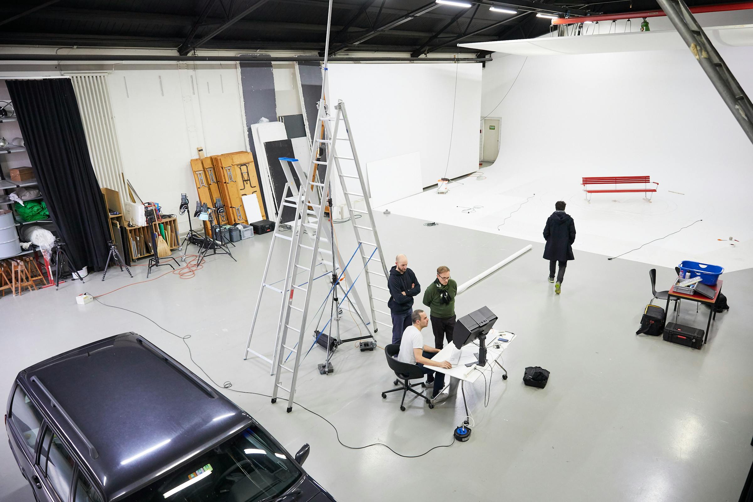 Backstage shot in a large photo studio with a garden bench in a white cove.