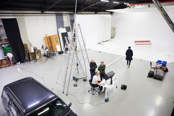 Backstage shot in a large photo studio with a garden bench in a white cove.