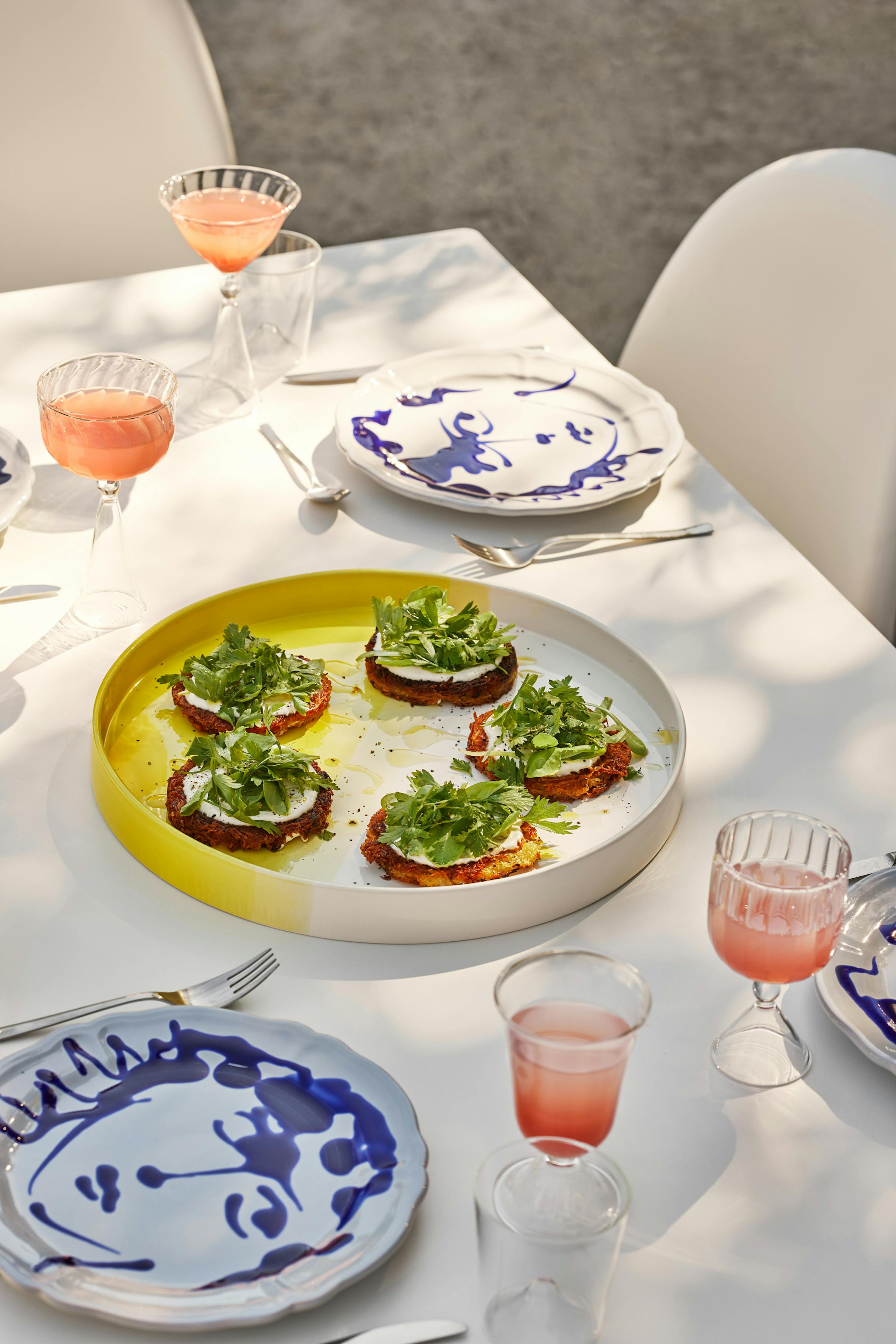 A yellow ceramic plate with Rösti, sour cream and fresh herbs in the shadow of a tree durign summer