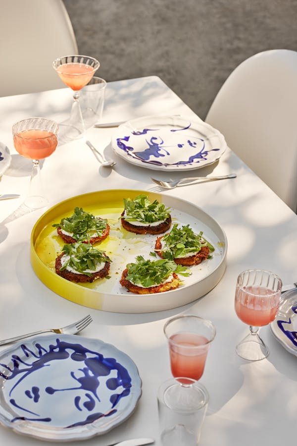 A yellow ceramic plate with Rösti, sour cream and fresh herbs in the shadow of a tree durign summer