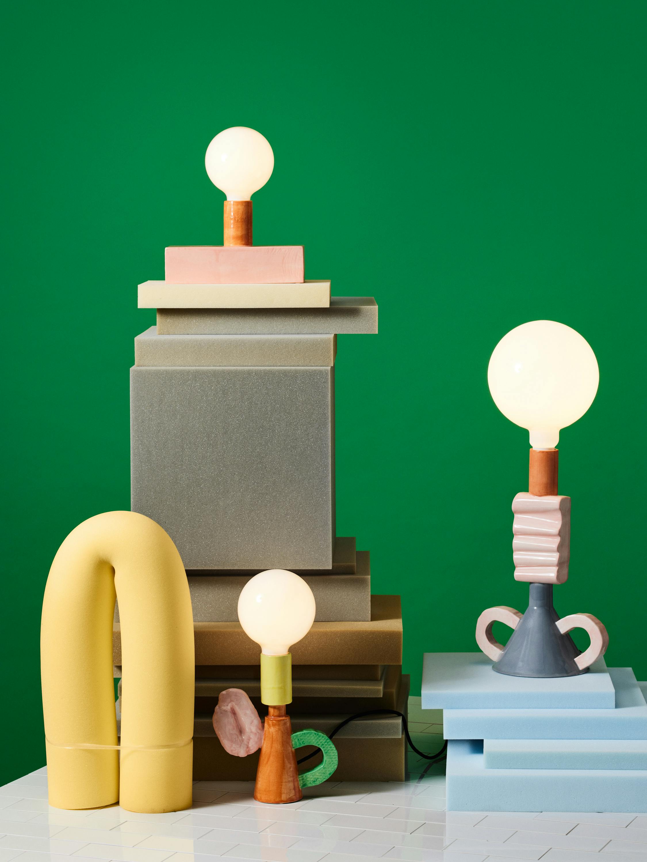Colourful porcelain lamps in a foam set design against a green background