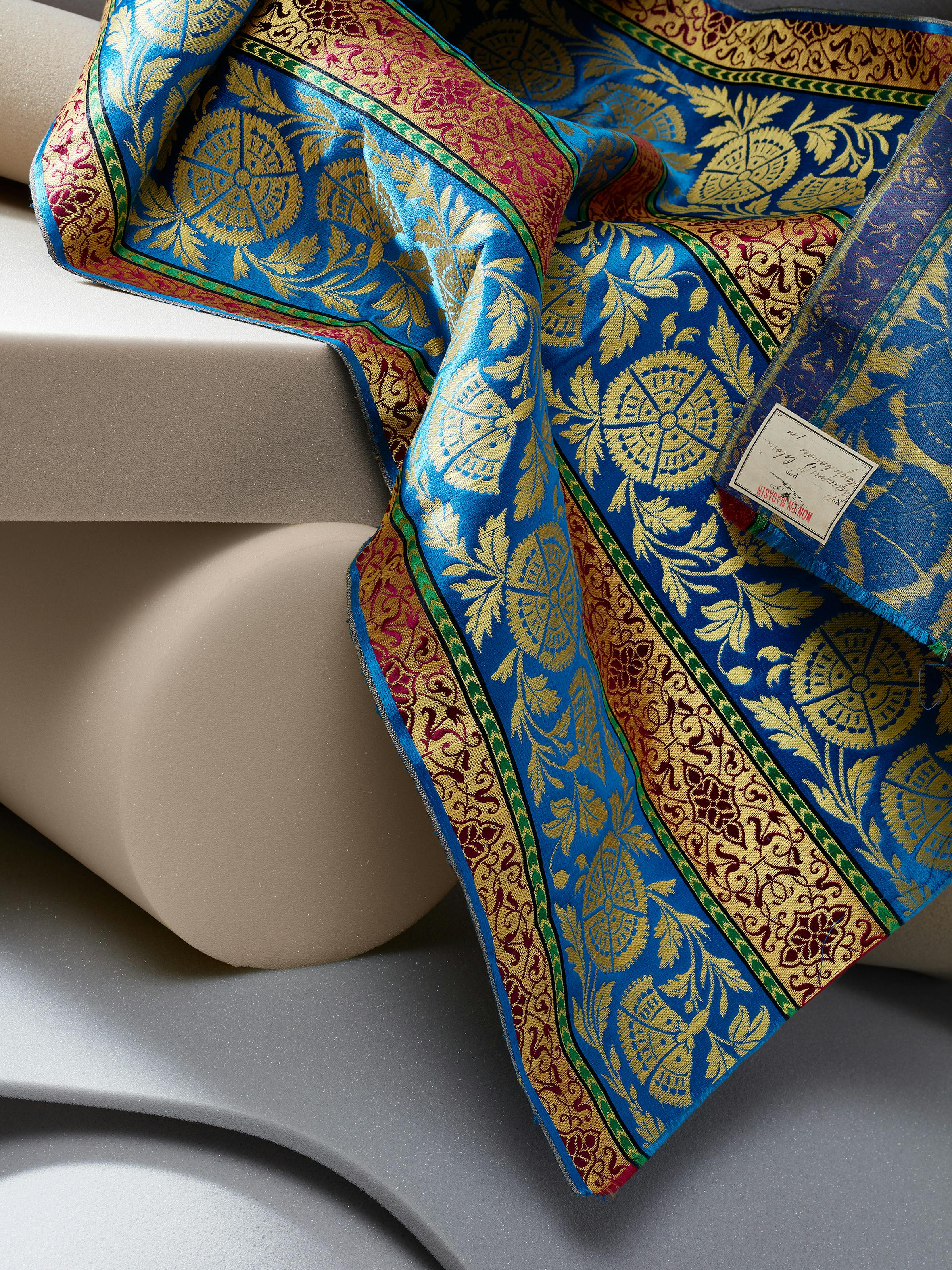 Close-up of a 19th-century fabric in blue and yellow colors on grey foam