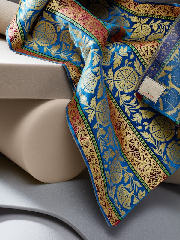 Close-up of a 19th-century fabric in blue and yellow colors on grey foam