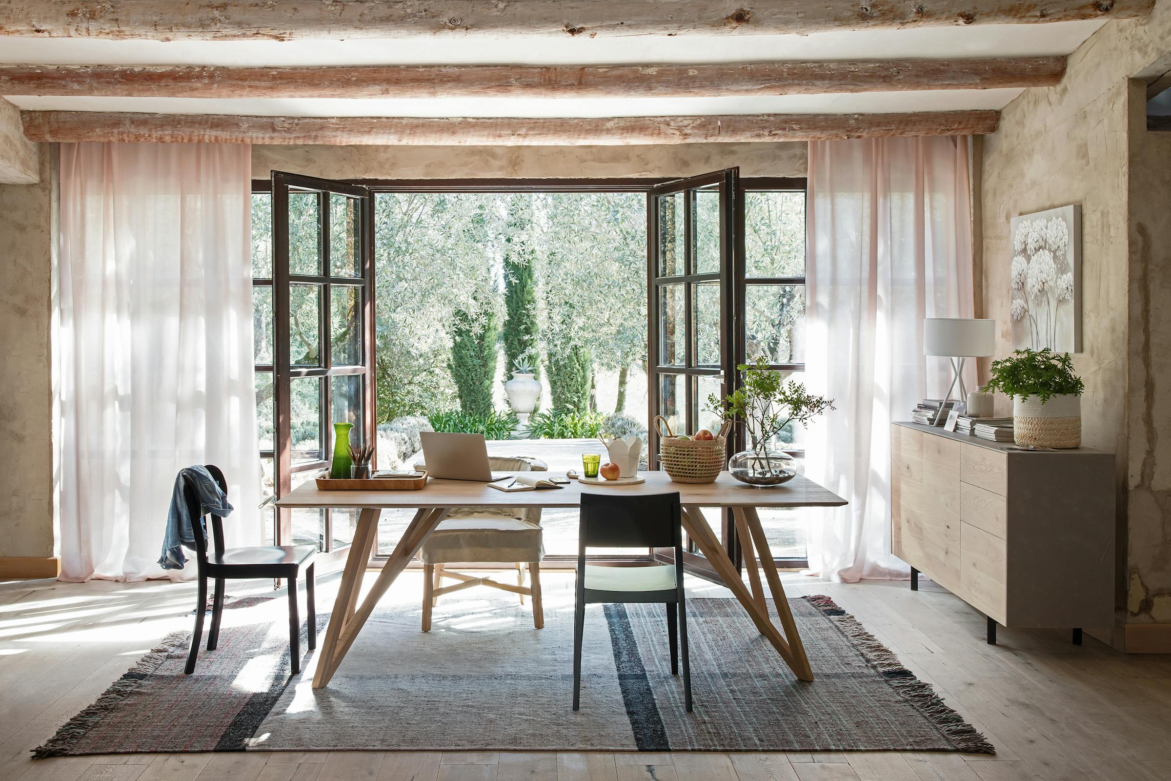 Office table in a Spanish country house with a view of the garden through the wide-open French doors