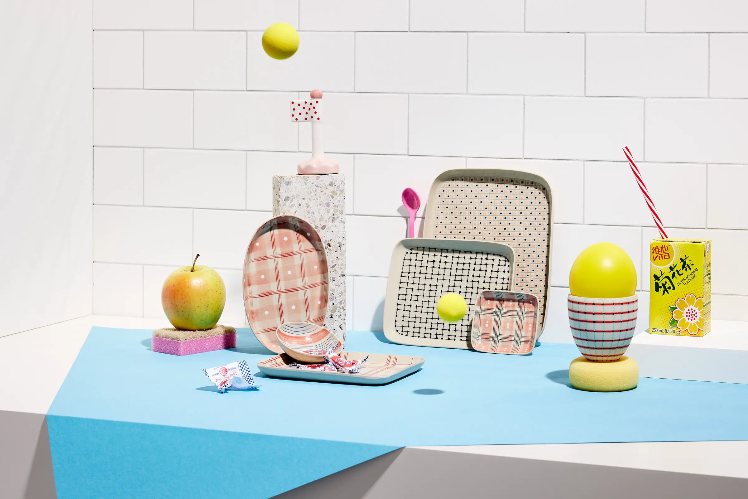 Various ceramic objects by Simone Fennel in front of a wall with tiles and a light blue paper