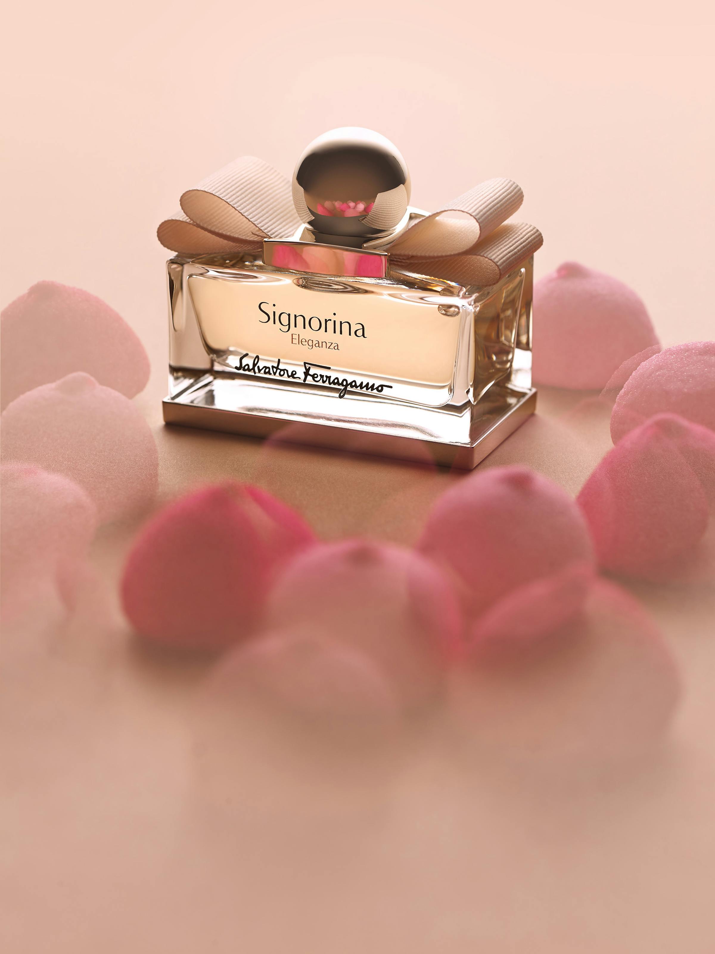 a Ferragamo perfume on a beige background with pink candies