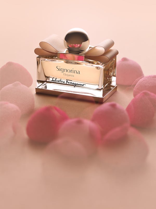 a Ferragamo perfume on a beige background with pink candies