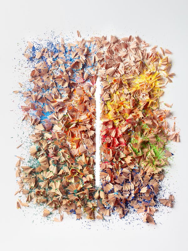 Colourful remnants from sharpening coloured pencils with a blank space in the shape of a pencil