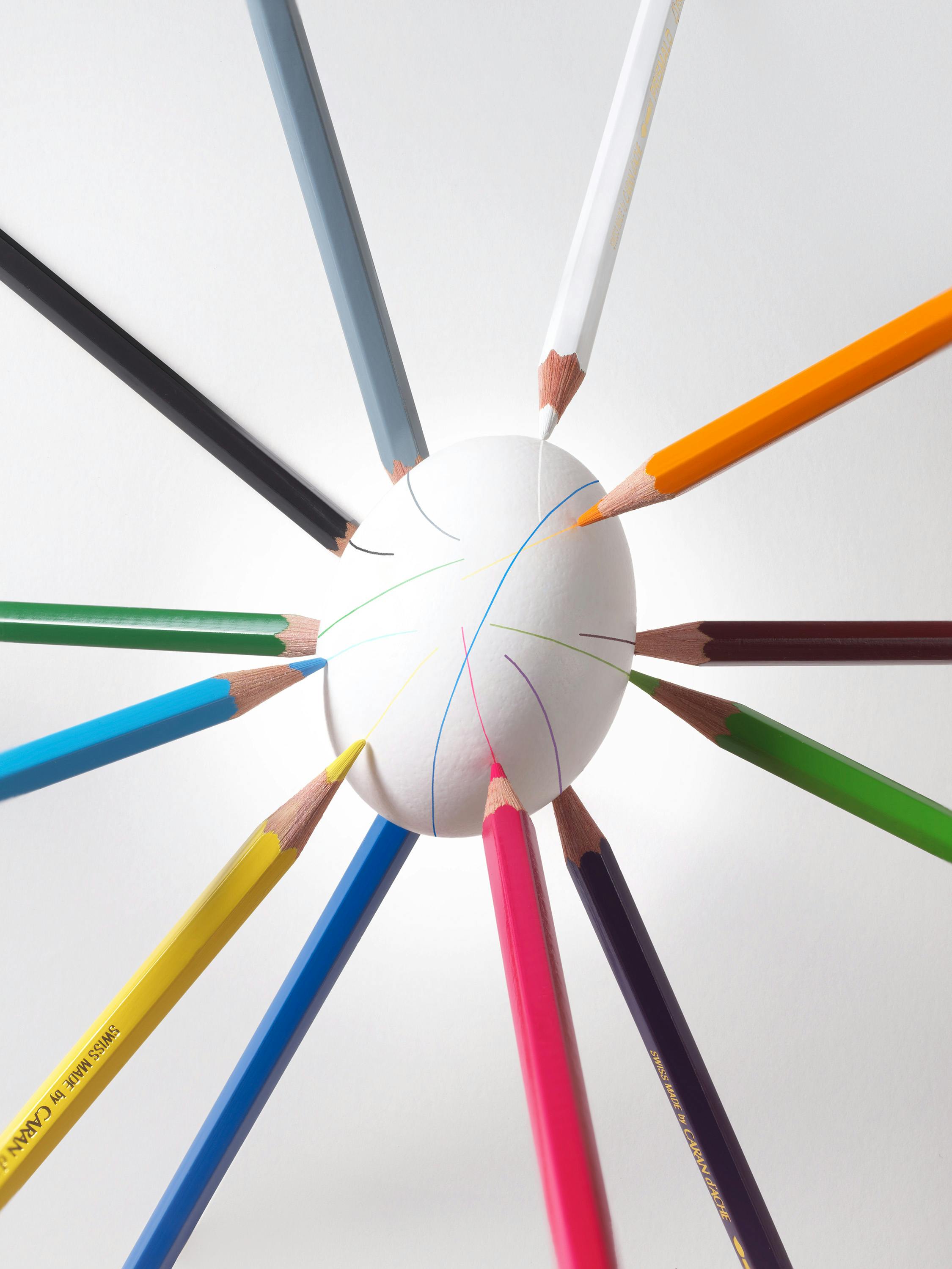Coloured pencils that balance an egg together and mark it with coloured lines