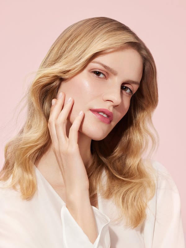 Beauty shot of a blonde woman in front of a light pink background