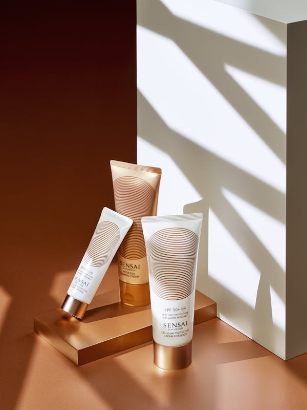 Sunscreen tubes on a bronze background with sharp graphic shadows