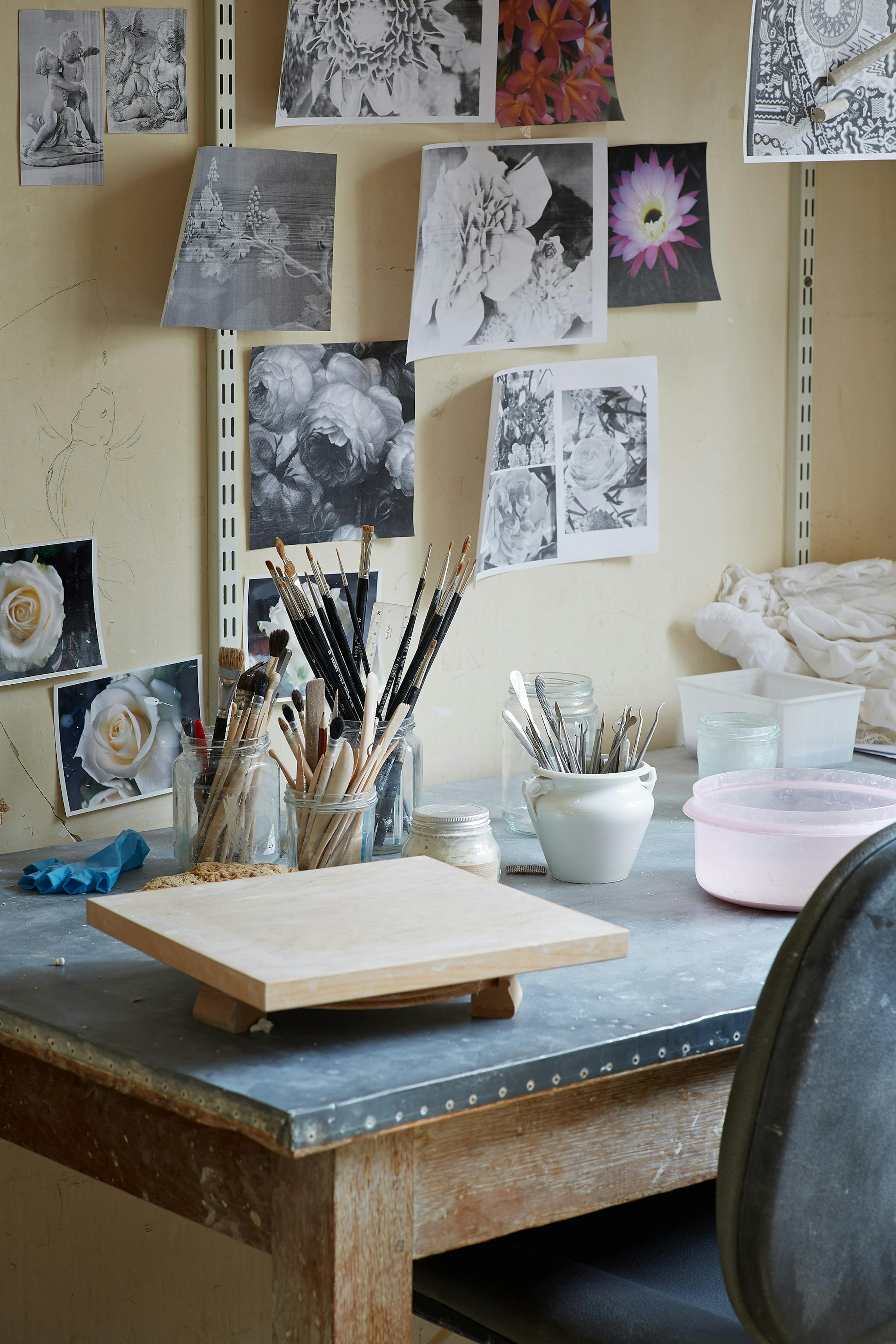 Table of a porcelain craftsman with photographs of flowers on the wall