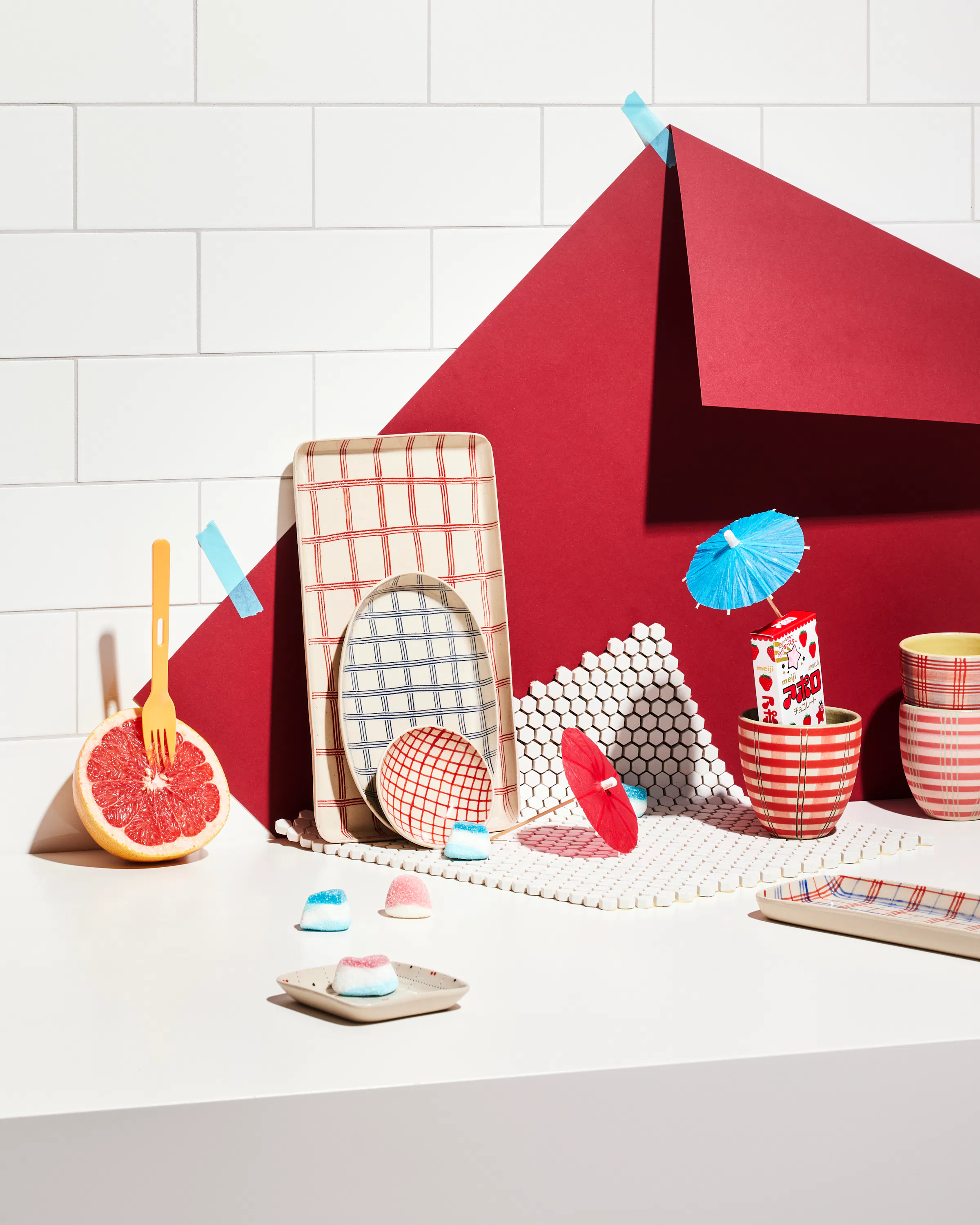 Various ceramic objects by Simone Fennel in front of a wall with tiles and a red paper