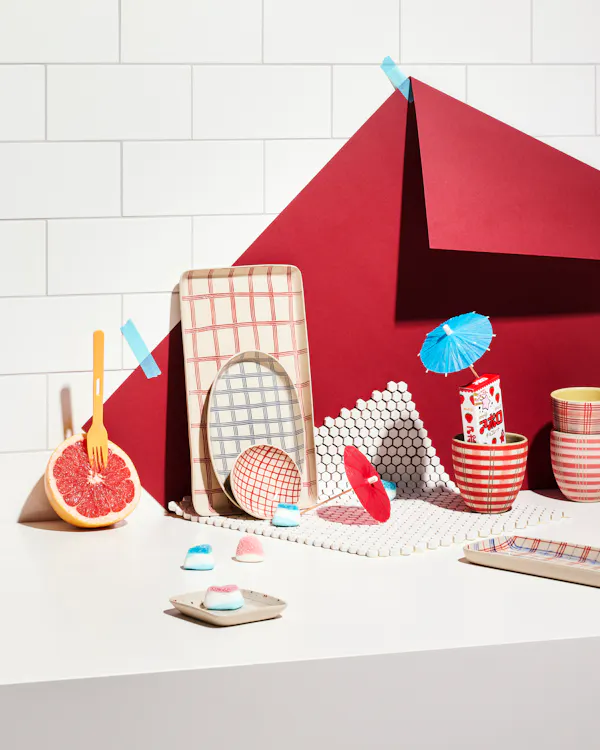 Various ceramic objects by Simone Fennel in front of a wall with tiles and a red paper