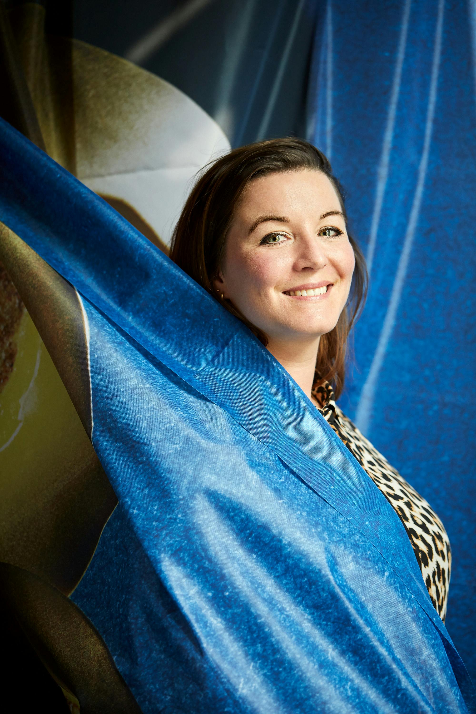Portrait of designer Carolien Niebling in front of a blue textile