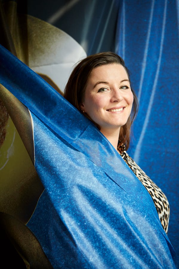 Portrait of designer Carolien Niebling in front of a blue textile