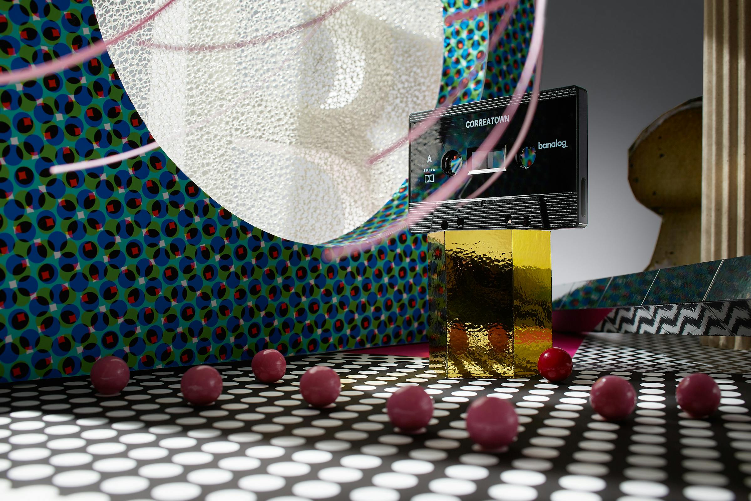 Cassette on a golden pedestal in a fantastic set design with blue pattern and pink balls