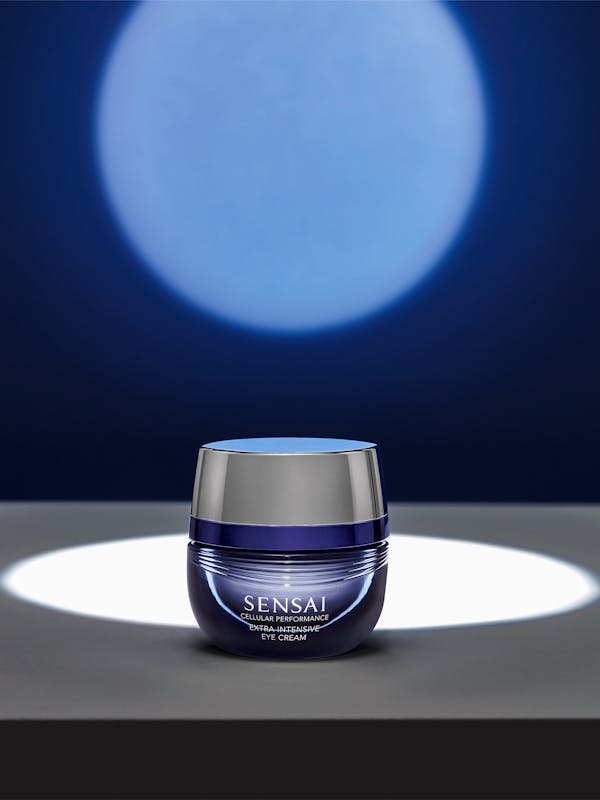 A jar of beauty cream in front of a dark blue wall with a spotlight
