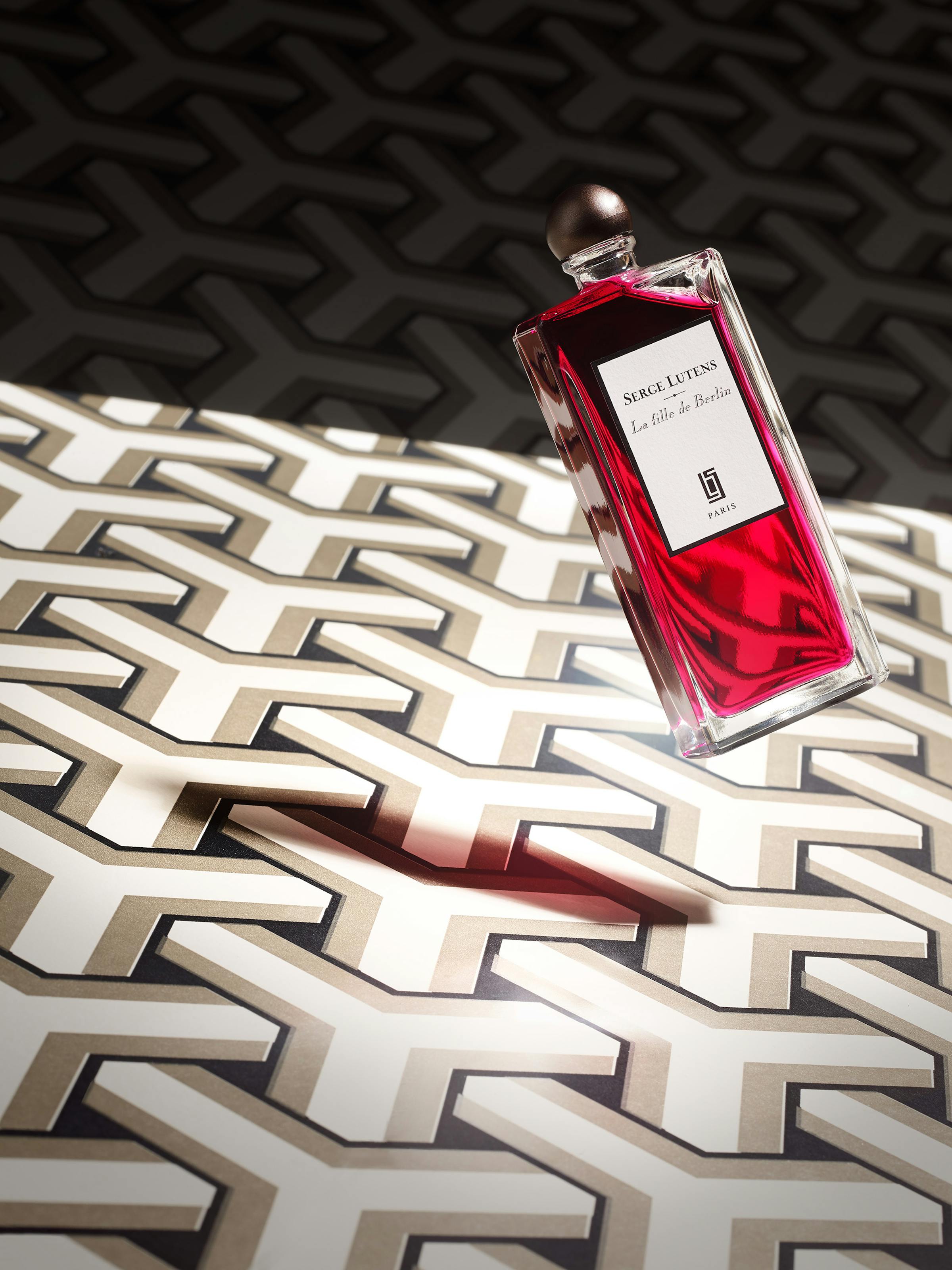 Red floating perfume bottle on graphic wallpaper