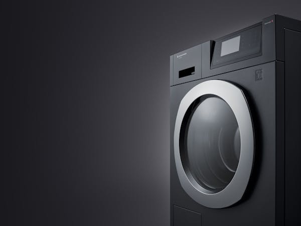 Close-up of a black washing machine against a black background
