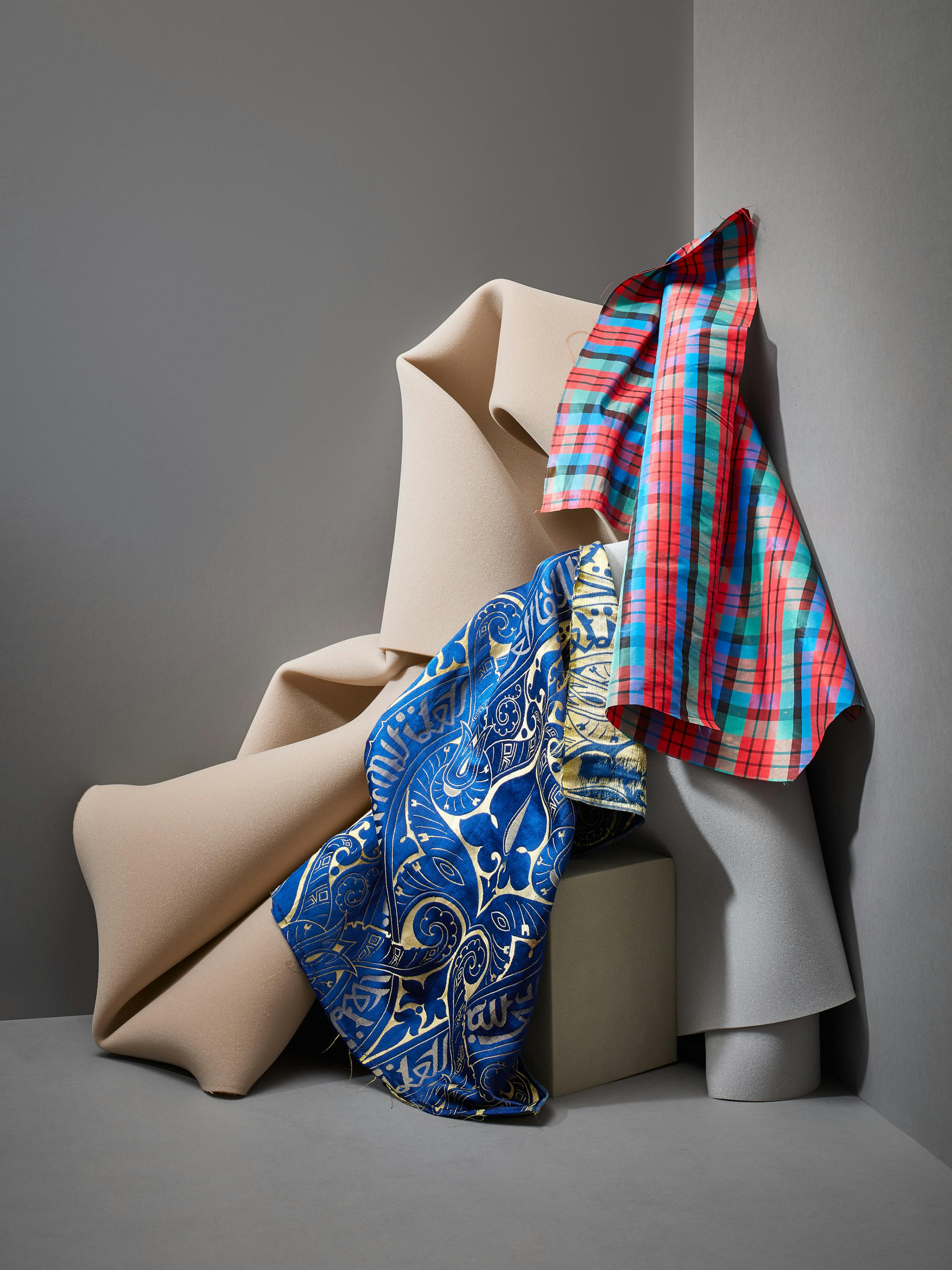  Colourful fabrics from the 19th century together with grey foam in a corner