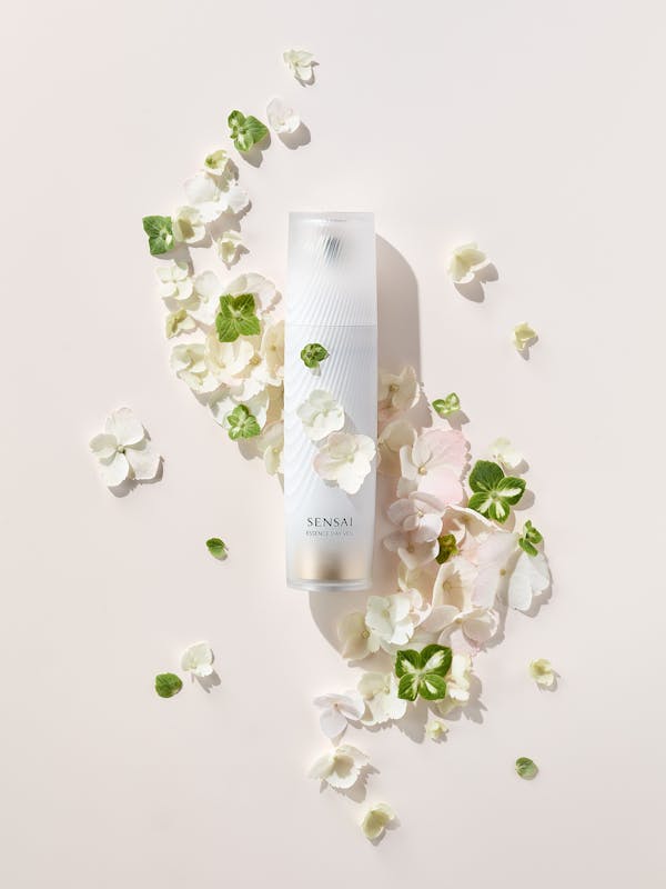 A white beauty product with green and pink flowers on a beige background
