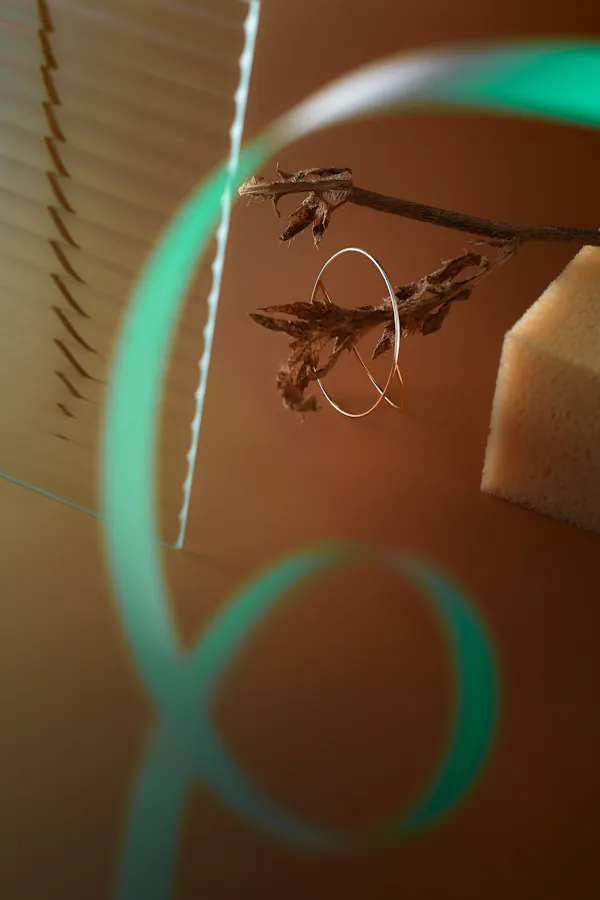 Earring on an orange-yellow background with a bright green paper loop