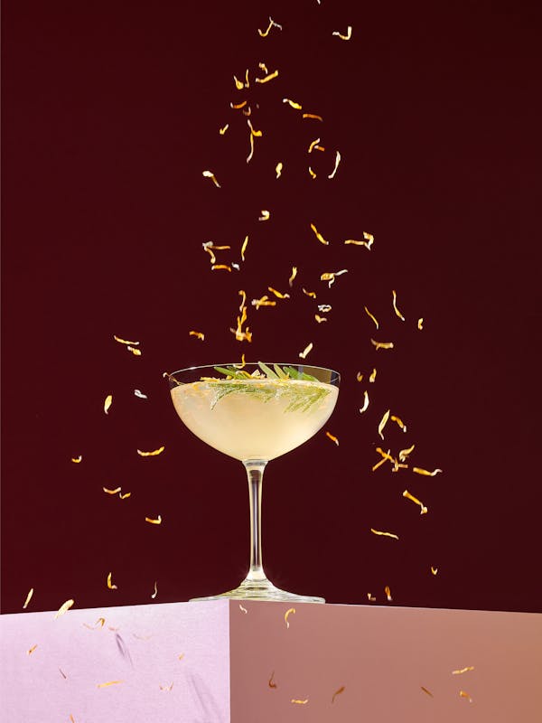 Cocktail on a pink base sprinkled with flowers from above