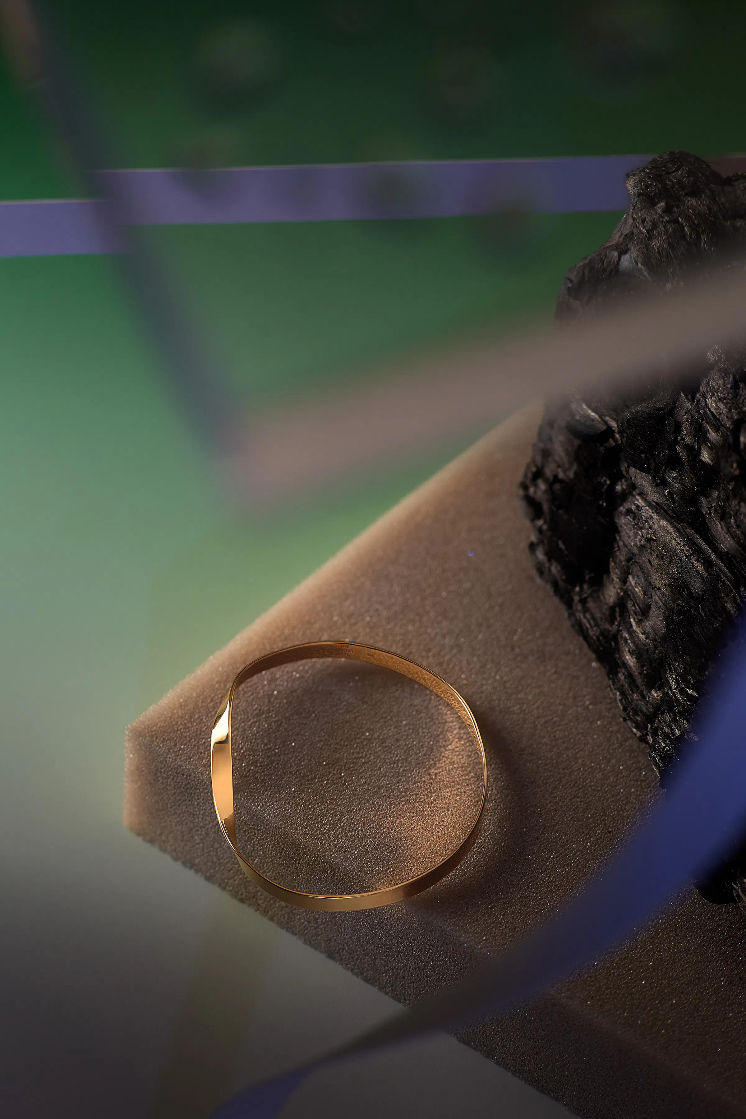 Golden arm ring on a piece of foam on a green background