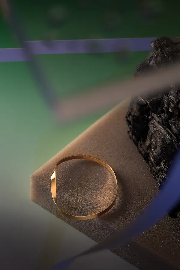 Golden arm ring on a piece of foam on a green background