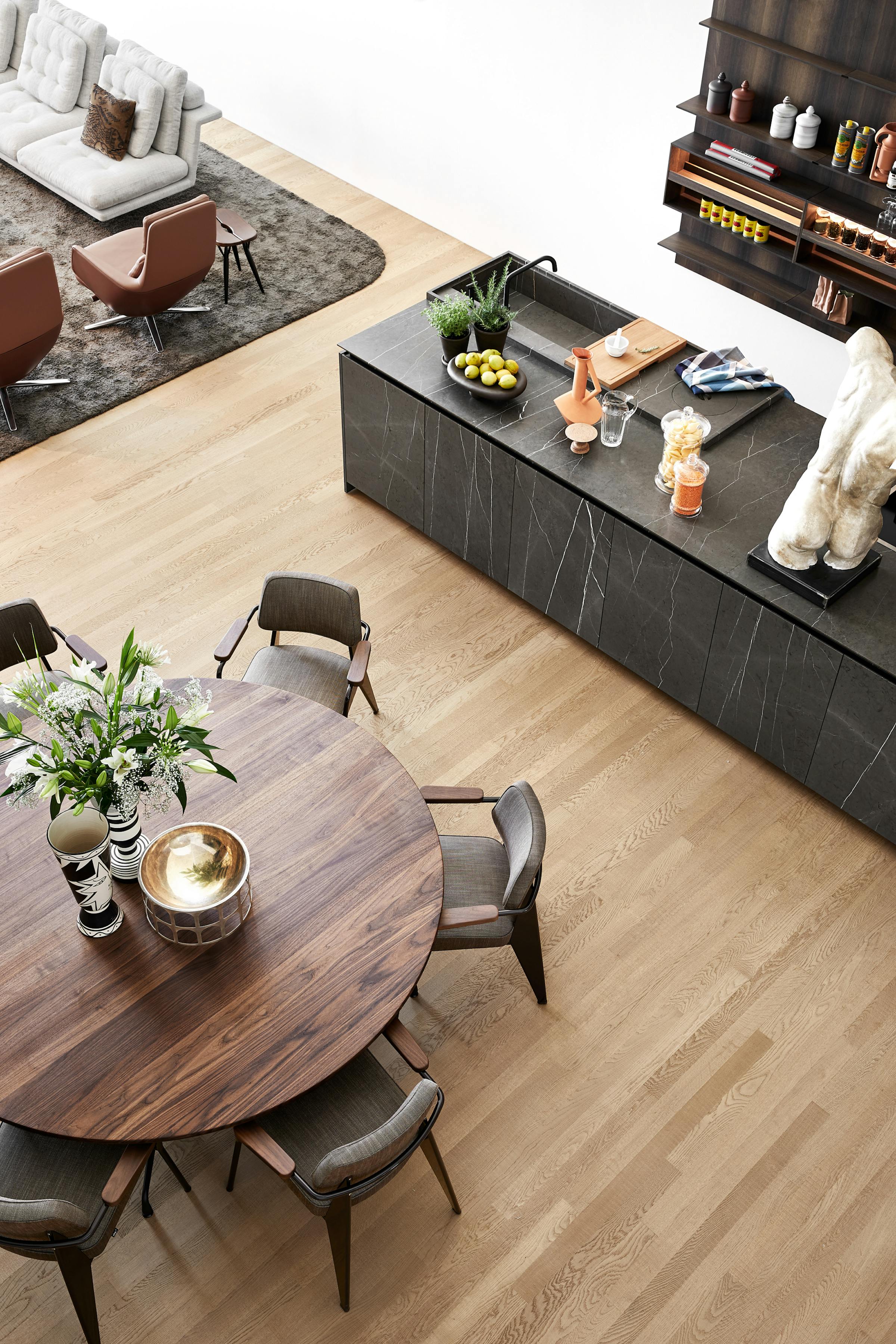 Top view of a round dining table made of dark wood with kitchen and sofa in the frame