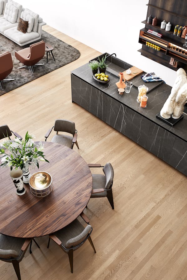 Top view of a round dining table made of dark wood with kitchen and sofa in the frame