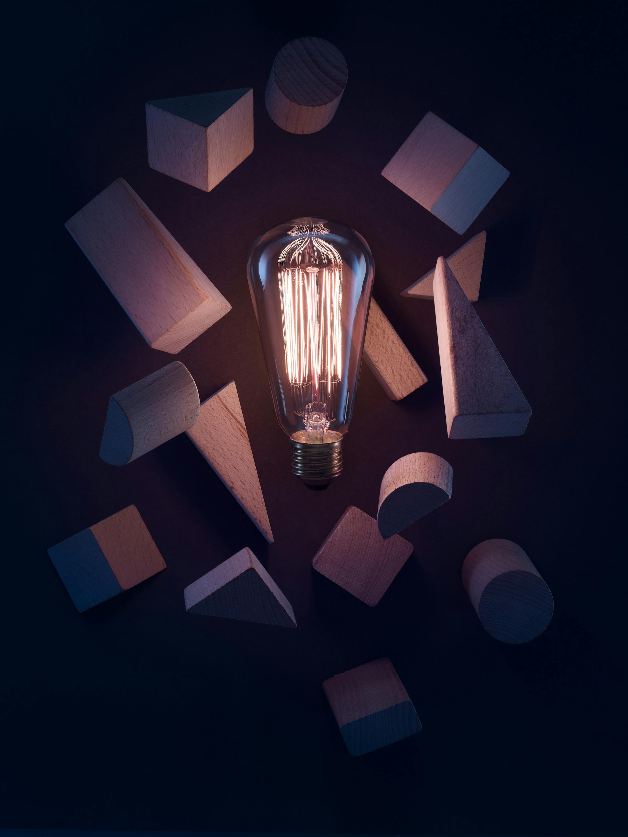 Light bulb with wooden building blocks in a dark blue set