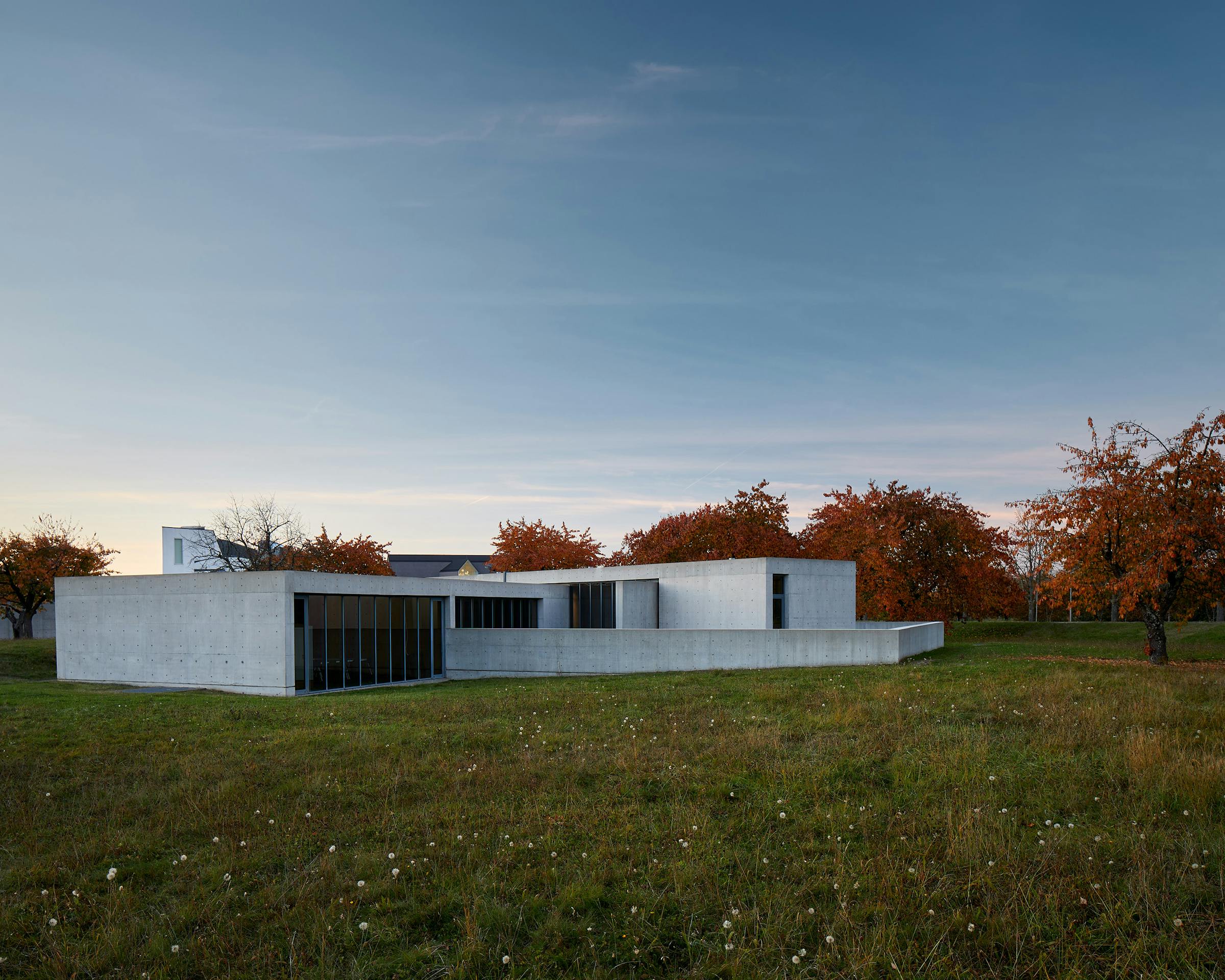 Modern concrete buildig by Tadao Ando in the darkening with red automnal trees
