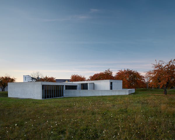 Modern concrete buildig by Tadao Ando in the darkening with red automnal trees