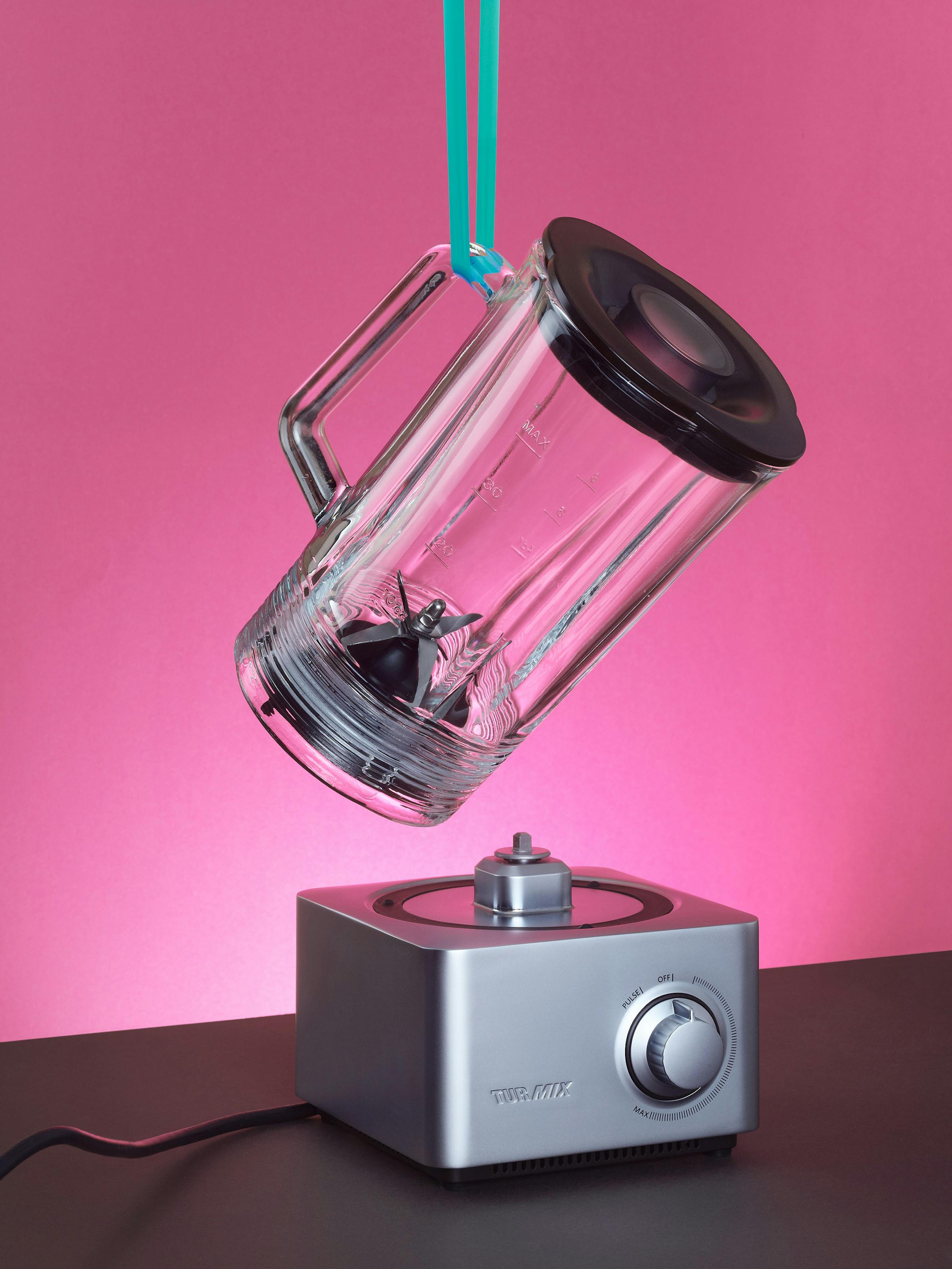 TurMix blender hanging on a green tape in front of a pink background