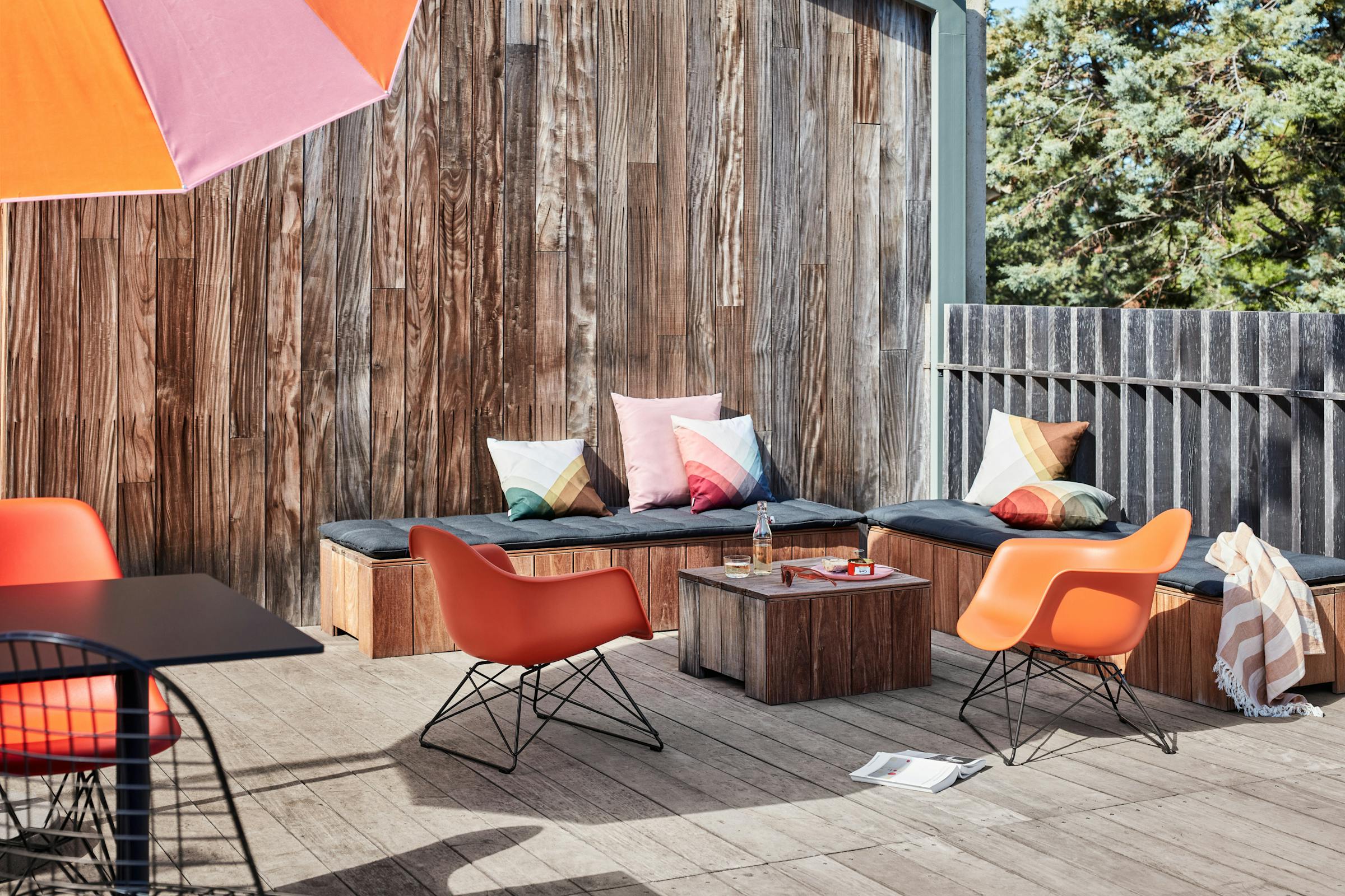 Lounge with two orange Eames armchairs bathed in bright sunlight