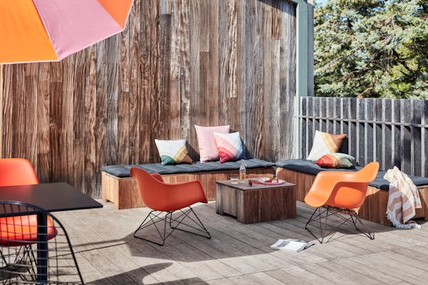 Lounge with two orange Eames armchairs bathed in bright sunlight
