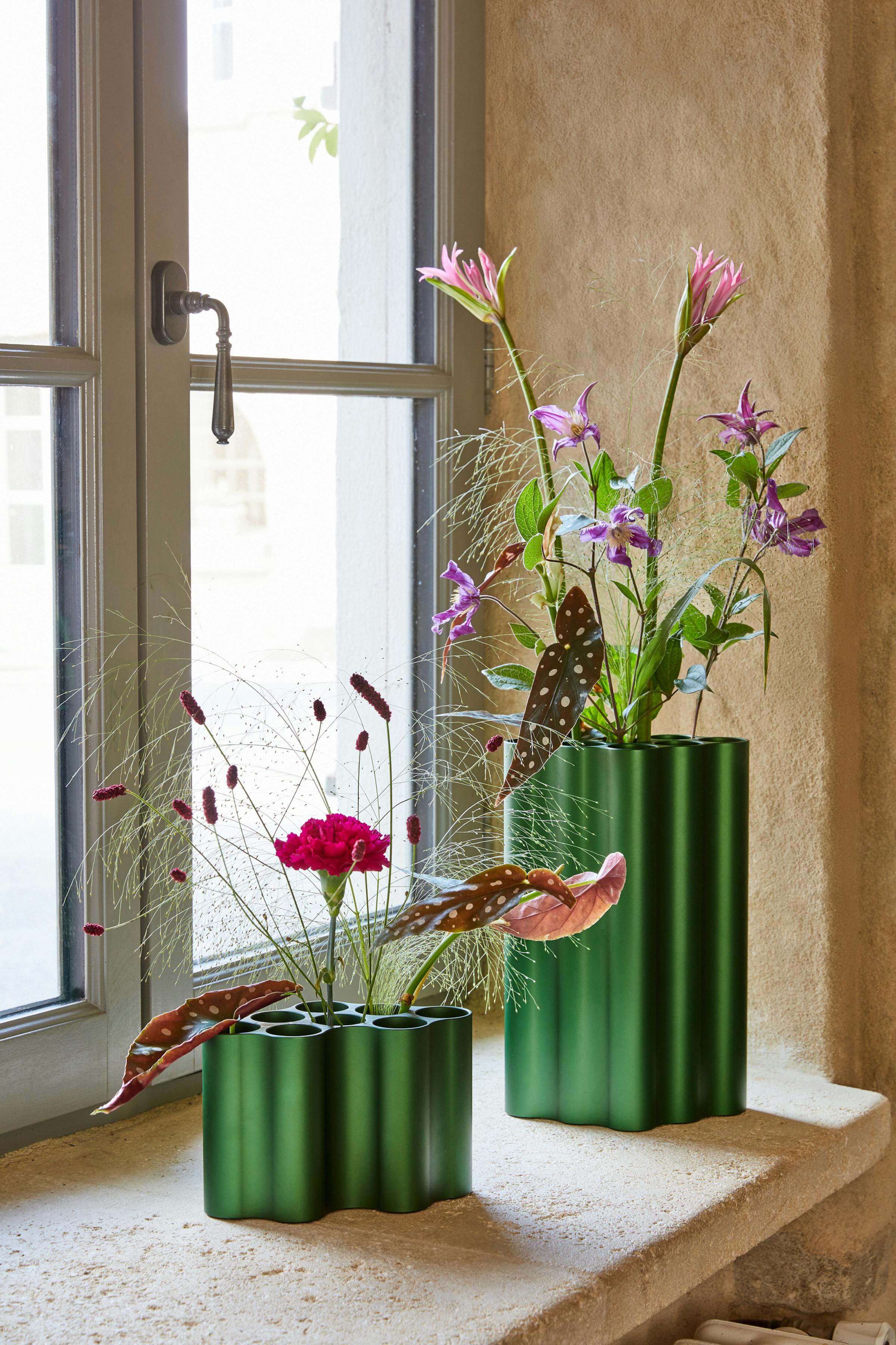 Two green Nuage vases by the Bouroullec brothers on a window sill with flowers