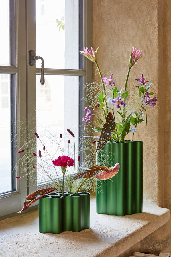 Two green Nuage vases by the Bouroullec brothers on a window sill with flowers
