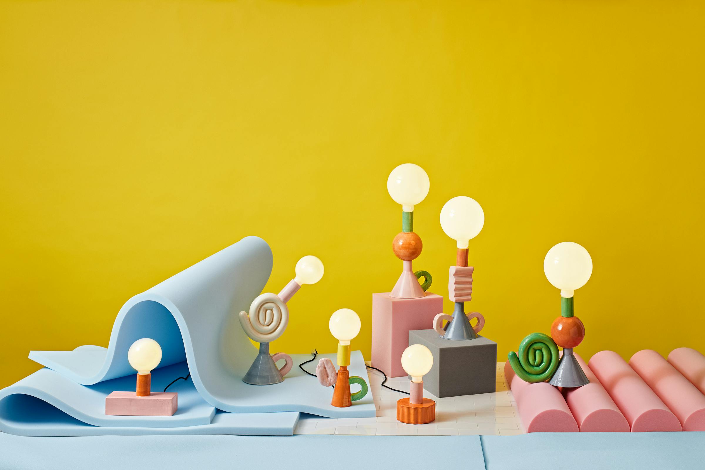 Colourful group of porcelain lamps in a foam set against a bright yellow background