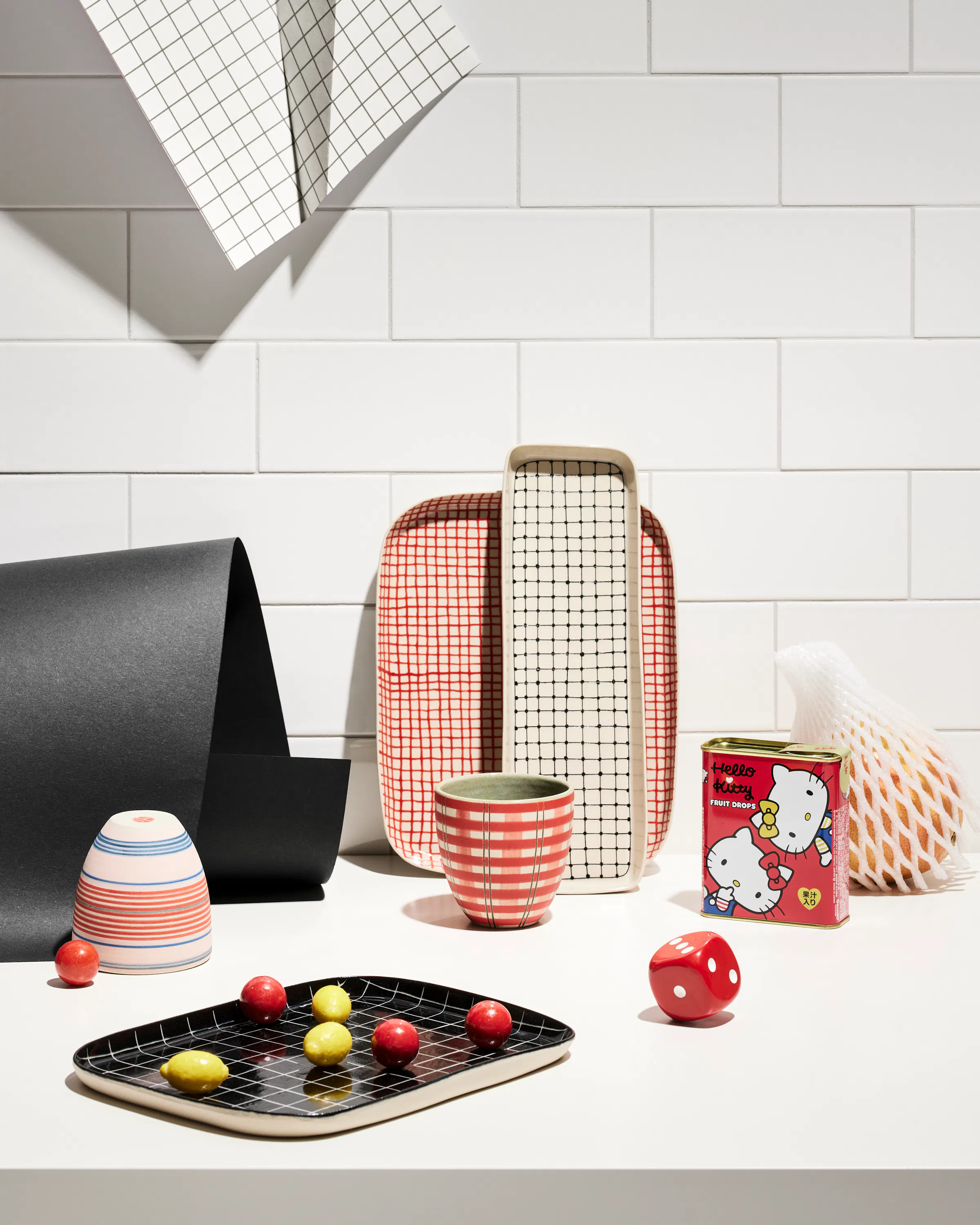 Various ceramic objects by Simone Fennel in front of a wall with tiles and a black paper