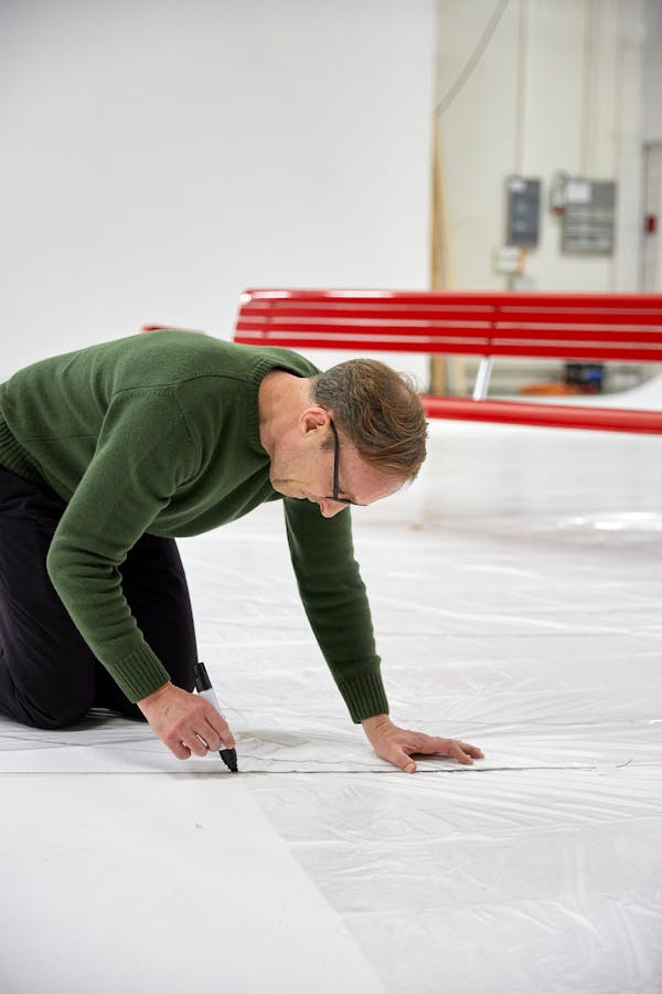 Frédéric Dedelley draws an outline on a white floor
